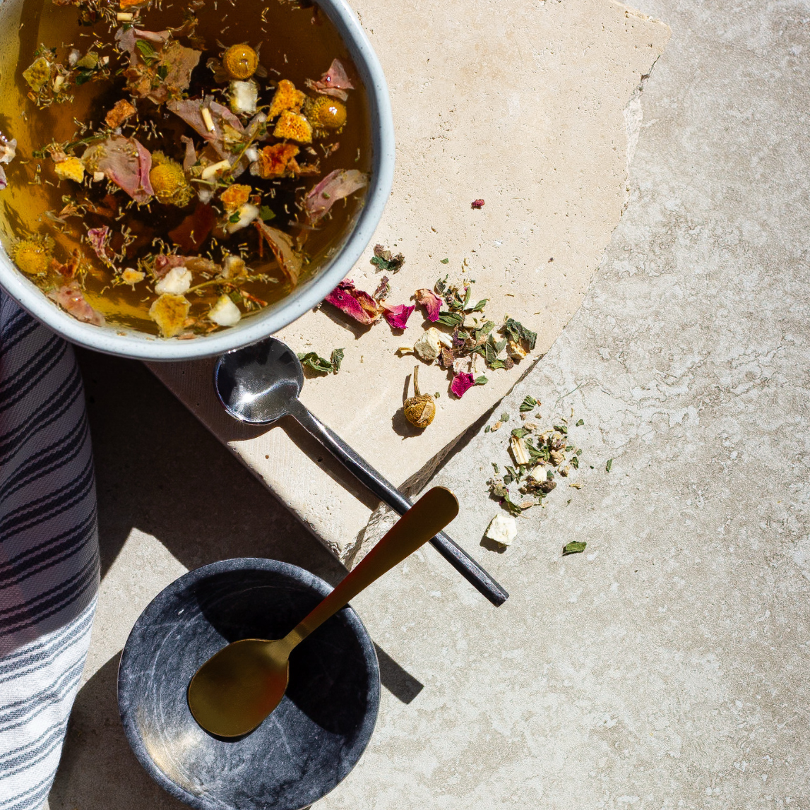 Three bowls with dried herbs and flowers on a concrete surface