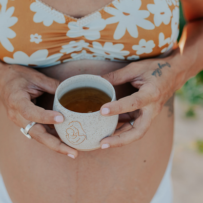 Person holding a small cup with a floral-patterned top