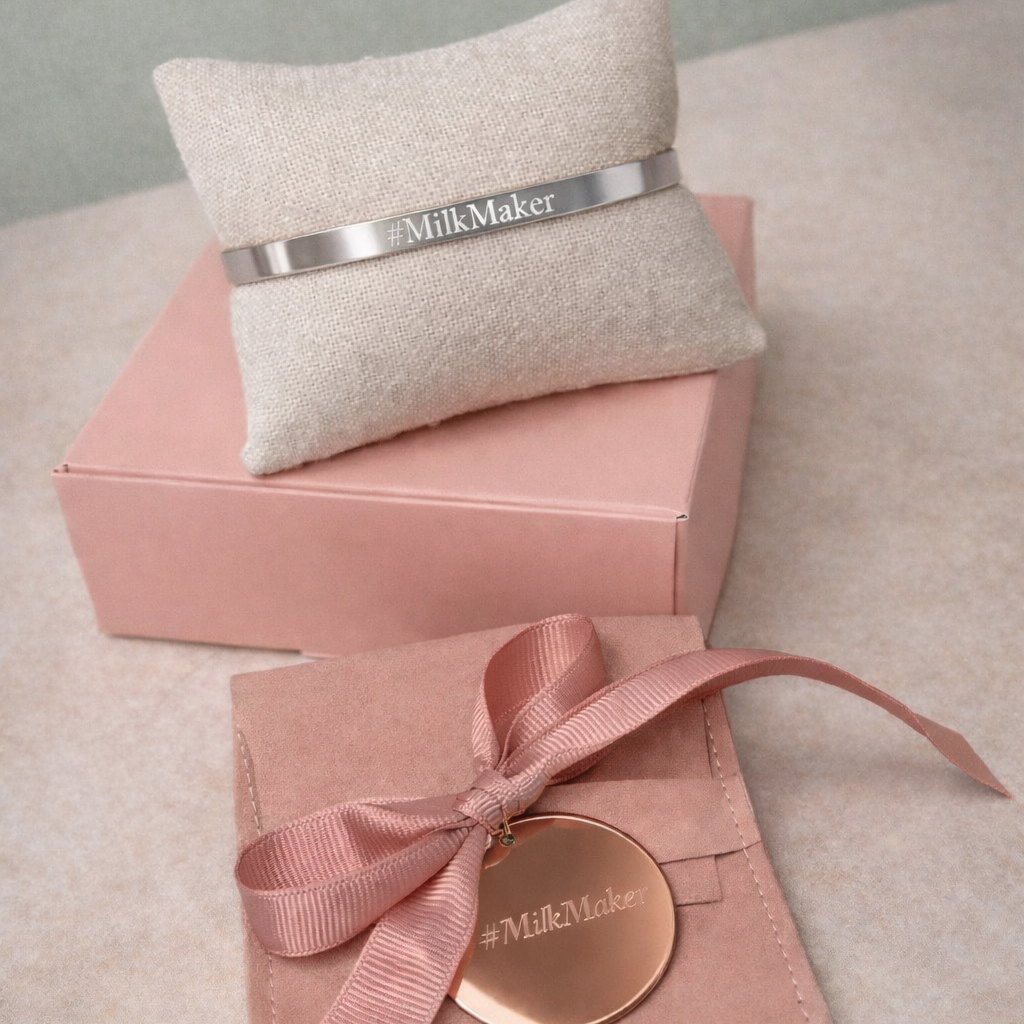 Pink packaging with a gold disc and ribbon, featuring 'Milk Maker' branding, on a light gray surface.