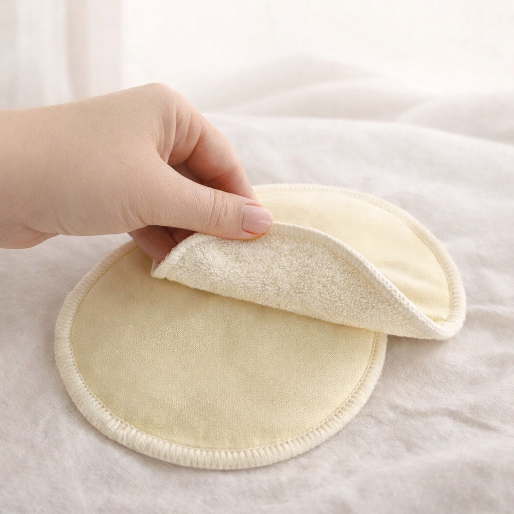 Hand holding a soft yellow circular fabric pad on a white background