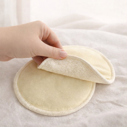 Hand holding a soft yellow circular fabric pad on a white background