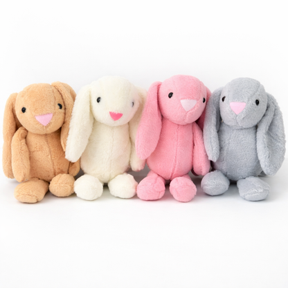 Four plush bunnies in brown, white, pink, and gray on a white background